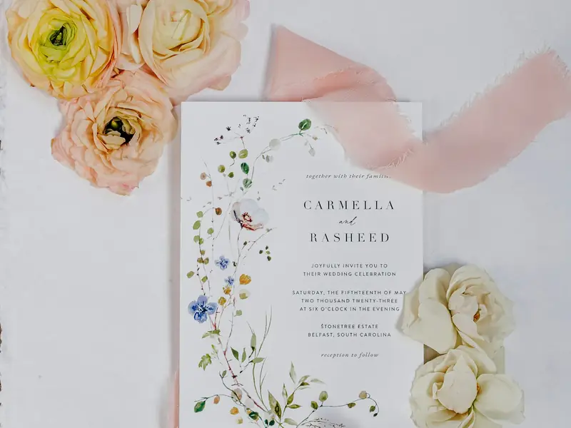 A floral wedding invitation surrounded by flowers