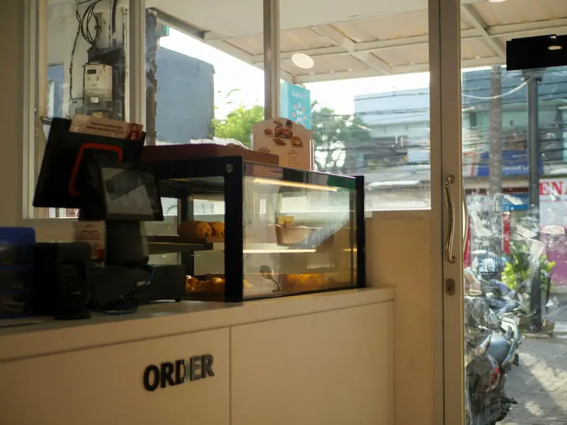 An order counter with a till and a pastry display