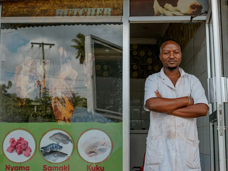 A shopkeeper standing in the doorway of his butcher's shop