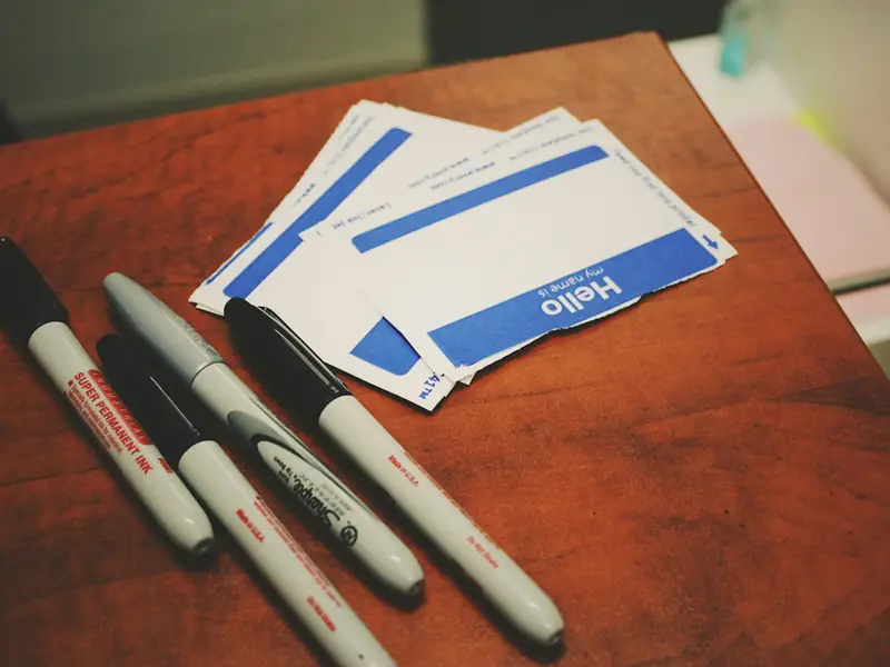 Blank 'Hello' name stickers and markers on a sign-up table