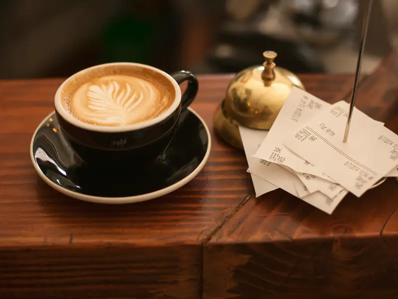 A coffee next to receipts on a café counter