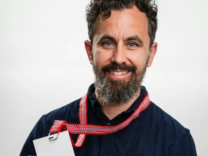 A smiling man wearing a name badge on a lanyard
