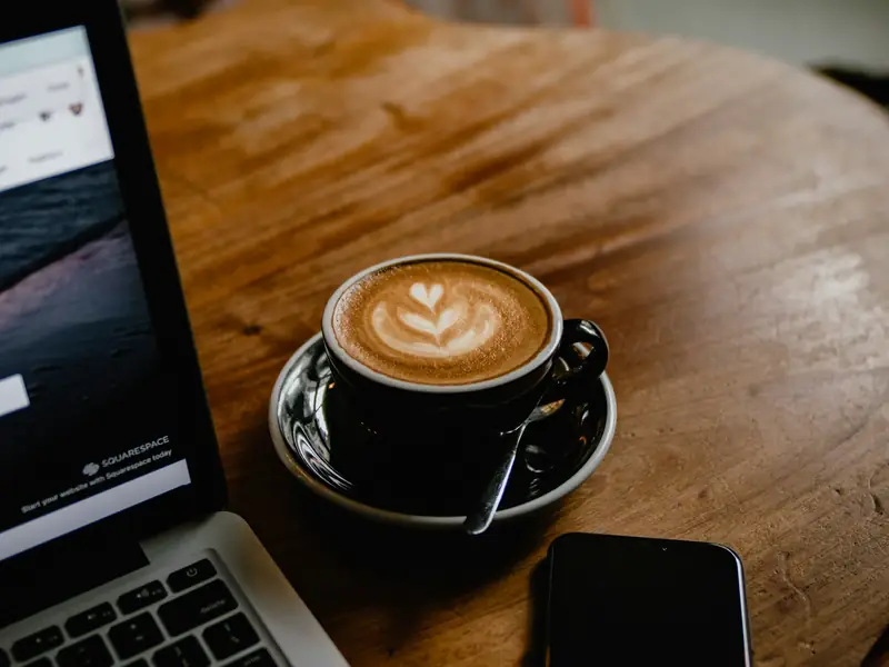 A latte and a laptop on a café table