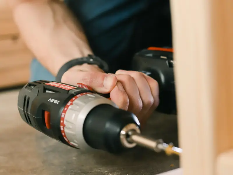 A hand drilling into a wooden board